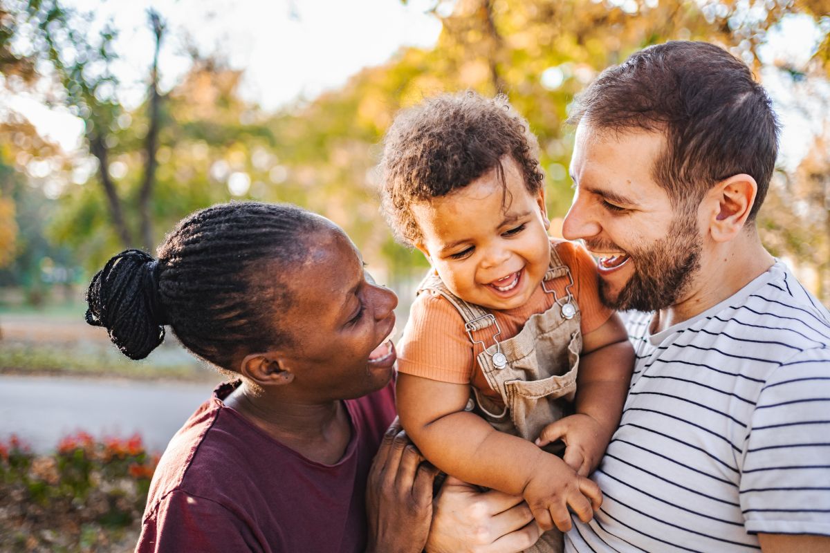 Two adults holding child laughing together