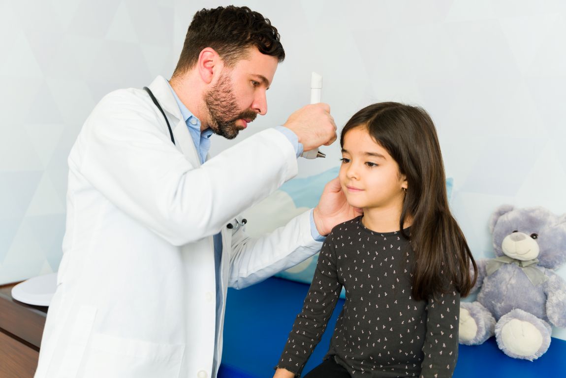 audiologist using otoscope at pediatric appointment to evaluate an ear infection