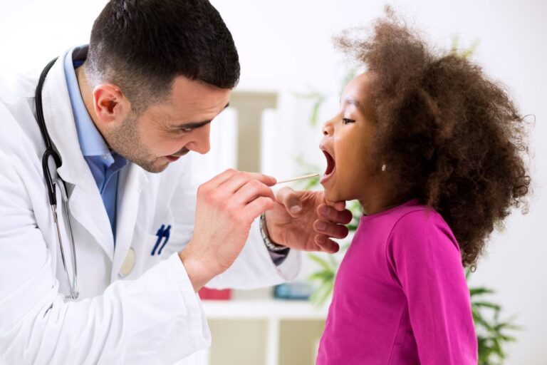 child with mouth open as doctor inspects tonsils